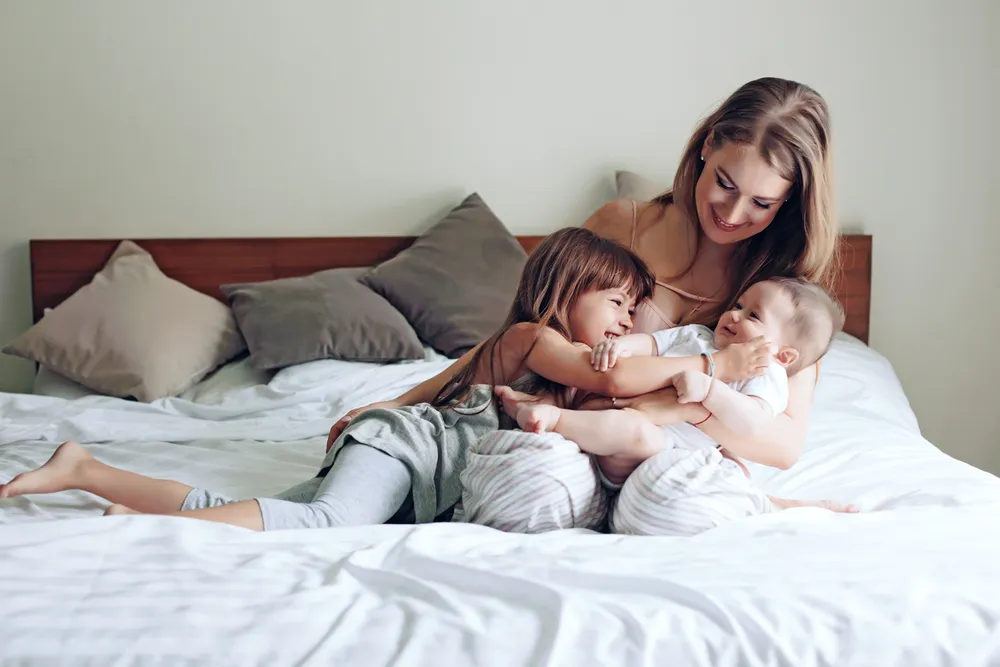 Mom with her children on bed cuddling