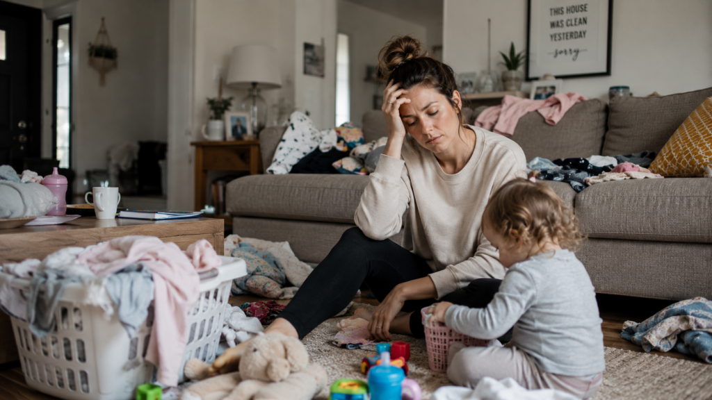 Overwhelmed mom sitting in the living room with her child during a stressful day